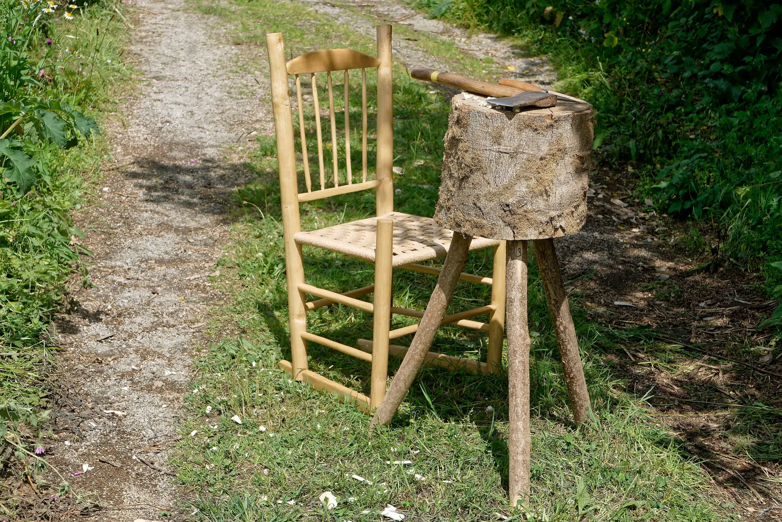 hand made chair and three legged work block with a hand axe on it